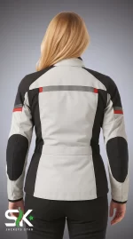 Rear view of a blonde female model wearing our manufactured light grey and black textile motorcycle riding jacket featuring high-visibility reflective striping with red accents and reinforced elbow panels.