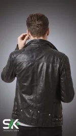 Rear studio view of our handcrafted men's black genuine leather biker jacket featuring quilted ribbed shoulder and sleeve padding with studded waist belt details.