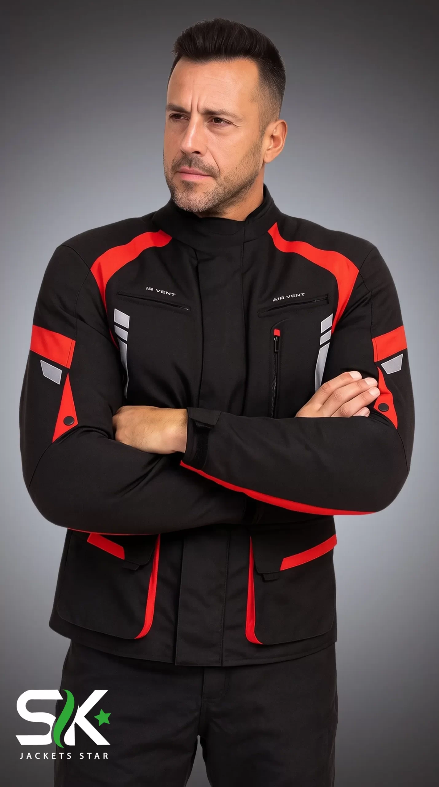 Men's Black & Red Ventilated Textile Touring Jacket Front View Front studio portrait of a male model with arms crossed wearing a black textile motorcycle jacket with red shoulder accents and zippered chest air vents.