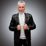 Front view of a men’s premium black leather biker jacket featuring classic wide lapels, silver metallic zippers, shoulder epaulettes, and a slim-fit design for bulk private label production.