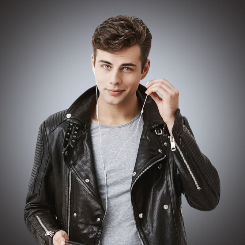Front view of a men’s premium black leather biker jacket featuring quilted ribbed sleeves, multiple silver zippers, wide notched lapels, and a rugged distressed finish for private label retail.
