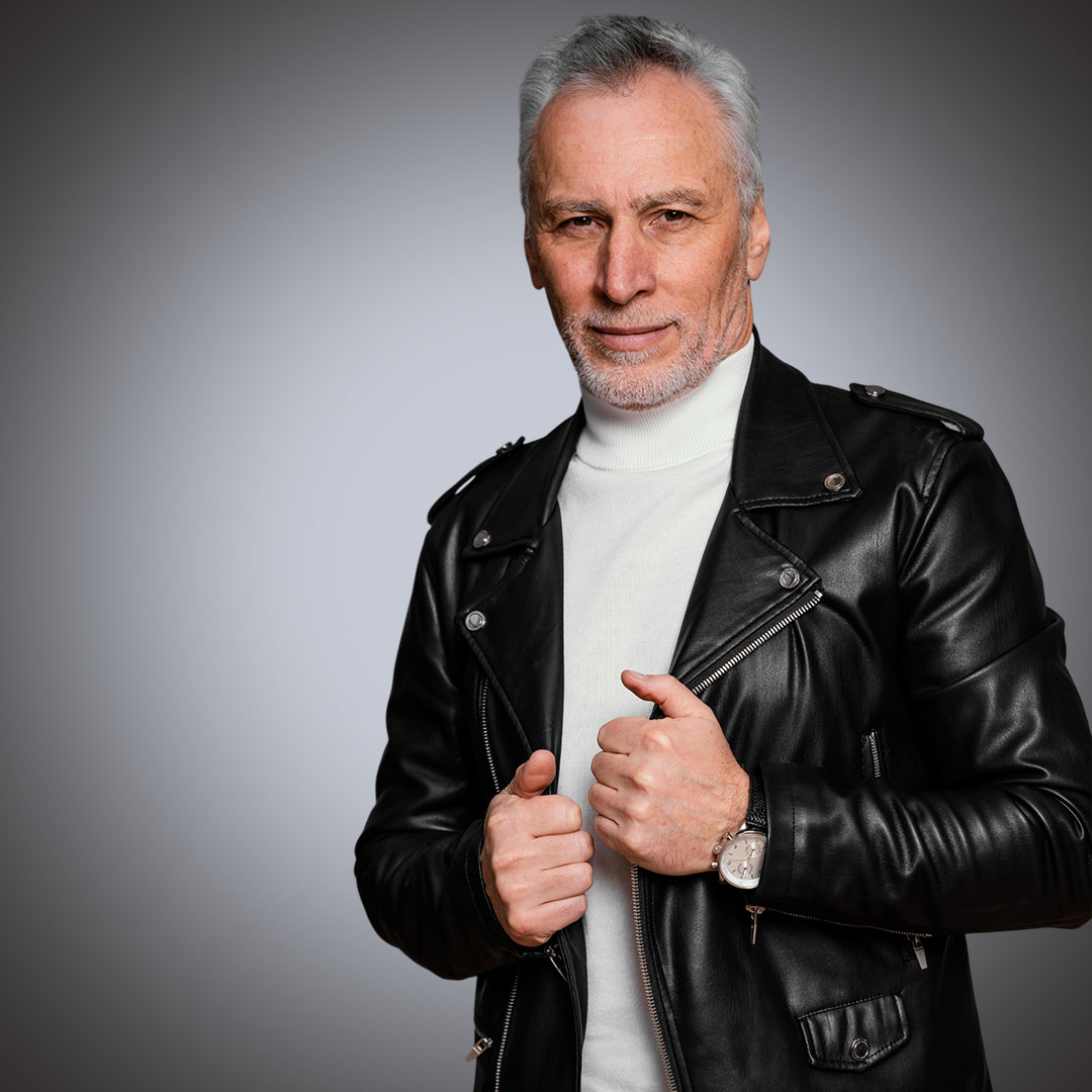 Close-Up Detail of Premium Leather Biker Jacket Side profile of a man wearing a high-quality black leather biker jacket with silver metallic hardware, featuring reinforced shoulder epaulettes and a professional slim-fit design.