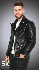 Front three-quarter studio portrait of a male model wearing our handcrafted black genuine leather asymmetric biker jacket with snap lapels and coin pocket.