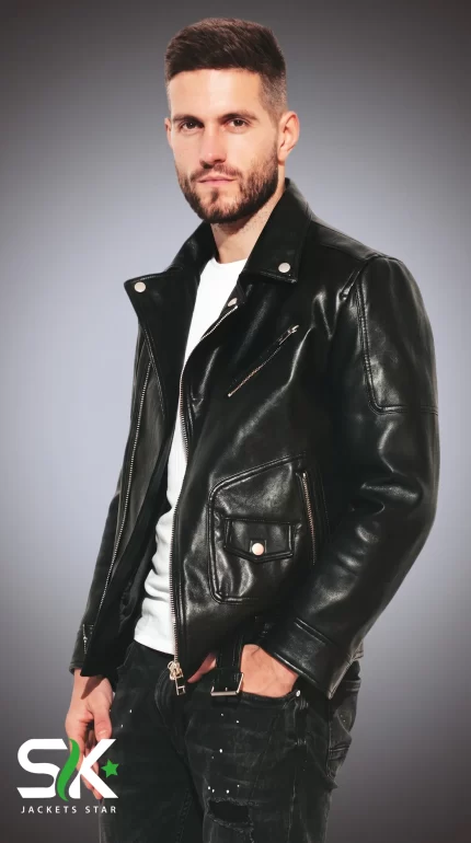 Front three-quarter studio portrait of a male model wearing our handcrafted black genuine leather asymmetric biker jacket with snap lapels and coin pocket.