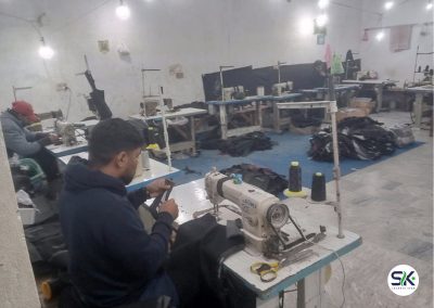 Production floor at Sialkot Jackets Star featuring skilled workers using Juki industrial sewing machines for high-volume jacket stitching and assembly.