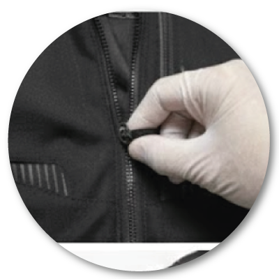 A close-up shot of a quality control inspector wearing a white glove, testing the zipper durability and alignment on a black technical jacket.