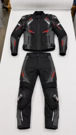 Flat lay front view of a black, grey, and red 2-piece Cordura biker suit with shoulder and knee protectors.