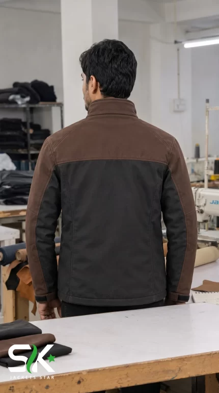 Back view of a male model wearing our custom manufactured two-tone brown and black softshell tactical jacket inside our production facility