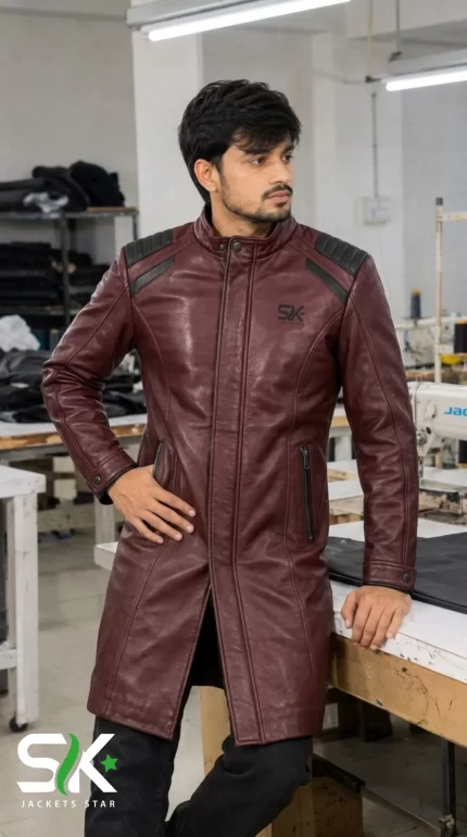 Front view of a male model wearing our custom manufactured longline maroon leather trench coat with black padded shoulders and stand collar inside our workshop.
