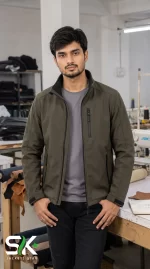 Front view of a male model wearing an olive green softshell tactical jacket in a garment factory studio setting.