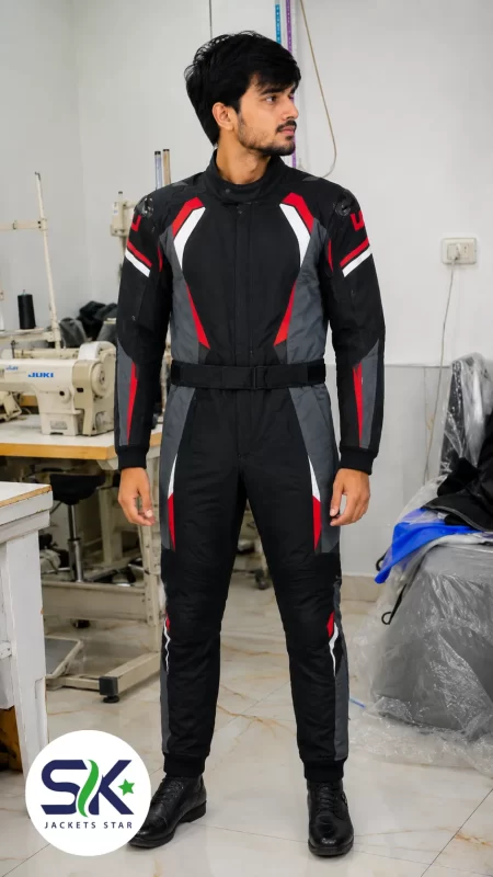 Male model wearing black, grey, and red full-body armored motorcycle racing suit inside Sialkot garment manufacturing factory.