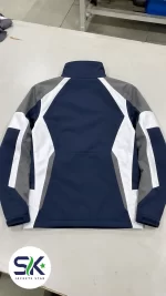Flat lay rear view of navy blue grey and white windproof softshell jacket manufactured on demand in Sialkot.