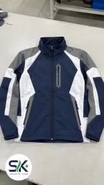 Flat lay front view of navy blue grey and white windproof softshell jacket manufactured on demand in Sialkot.